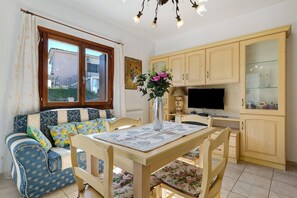 A cozy living room with a sofa, a wooden dining table, and a television.