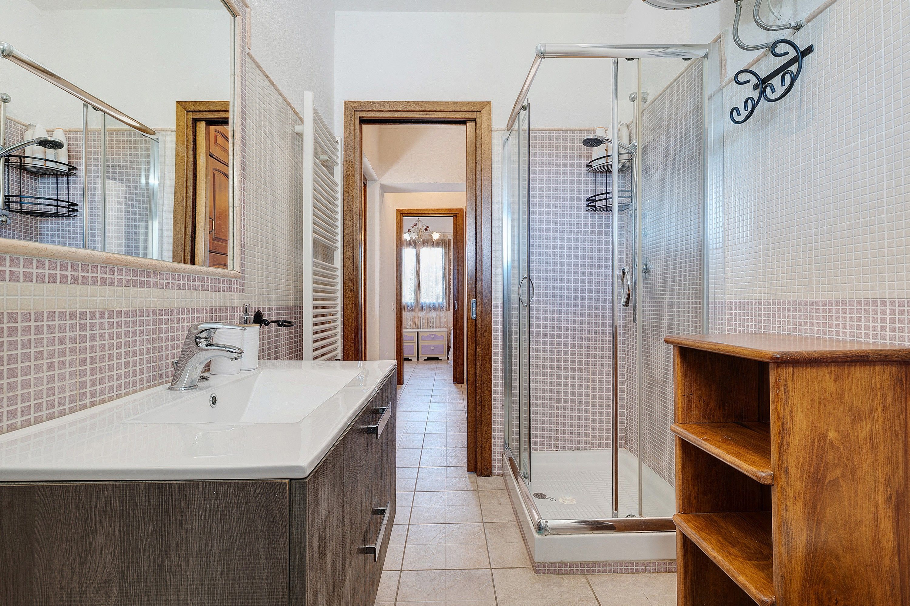 A modern bathroom with a large mirror, a shower enclosure, and a vanity with a sink.