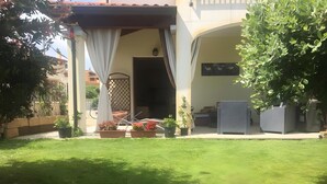 Un patio couvert agrémenté de plantes en pot et d’un espace aménagé pour s’asseoir.