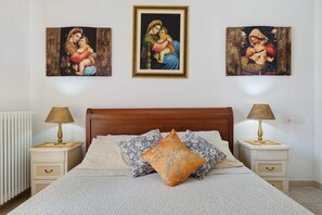 Ein Schlafzimmer mit einem hölzernen Bett, zwei Nachttischen mit Lampen und drei gerahmten Bildern an der Wand.