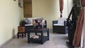 Une pièce comprenant un canapé, une table ornée d’un vase décoratif, un petit tabouret en bois et un paravent pliant.