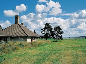 A rustic house with a tiled roof and chimneys, surrounded by a grassy field and a large tree. - 2 Rooms, Standard, 2+2 People, 48m2 (Karrebæksminde)