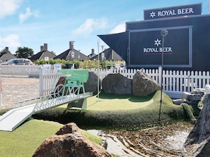A water feature with rocks and a bridge, a sign for 'ROYAL BEER', and a white picket fence. - 2 Rooms, Standard, 2+2 People, 48m2 (Karrebæksminde)