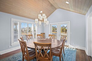 A dining room with a wooden table and chairs, large windows with blinds, and a view of the outdoors. - 360 Views, Rooftop Deck, Across from Beach Access - 413 Tarpon Blvd (Fripp Island)