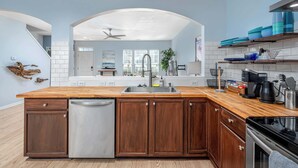 Una cocina con una isla de madera, electrodomésticos de acero inoxidable y vista al área de estar.