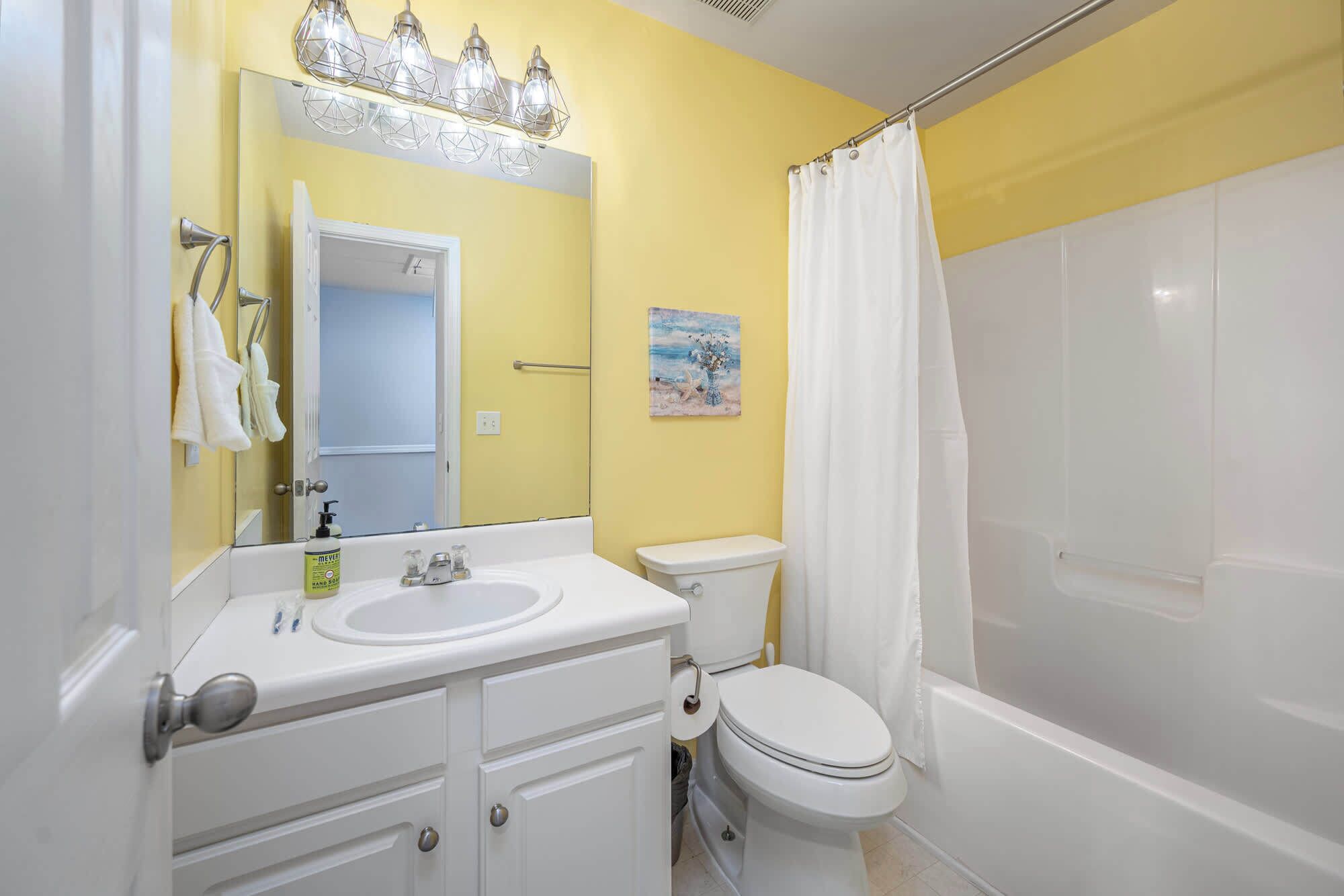 Un baño con lavamanos, inodoro y cortina de ducha blancos.