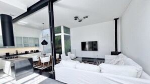 Un espace de vie moderne et minimaliste comprenant une cuisine, un coin repas et un grand canapé blanc.