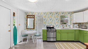Cocina con armarios verdes, estufa de acero inoxidable y encimera blanca.