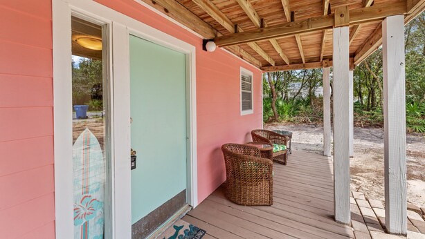 Un porche cubierto con muebles de mimbre y una decoración de tabla de surf.