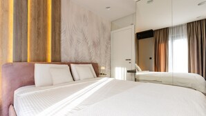 Ein Hotelzimmer mit einem großen Bett, einer Wand mit Holzvertäfelung, einem Spiegel und einem Fenster mit Vorhängen.