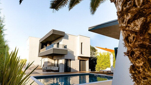 Ein modernes, zweistöckiges Haus mit Swimmingpool, Außenbereich und einem großen Baum im Vordergrund.