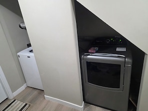 Ein Waschraum mit Waschmaschine, Trockner und einem kleinen, weißen Gerät, vermutlich ein Kühlschrank.