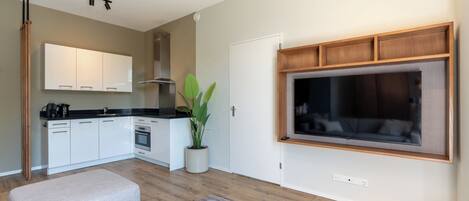 Una cocina moderna con armarios blancos, encimera negra y horno integrado.