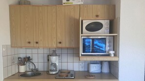 Ett kompakt kök med träskåp, en kaffebryggare från Bosch, en mikrovågsugn, en brödrost och en diskmaskin.