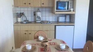 Ett litet pentry med mikrovågsugn, kaffebryggare och brödrost. Där finns ett bord med en duk, samt flera koppar och fat.