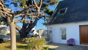 Et hus med garage, et træ på gårdspladsen og en bil foran.