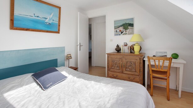 A bedroom with a bed, a desk, a chair, a lamp, and two paintings on the wall. - Spacious house in Locquirec with terrace, 300m from the beach (Locquirec)