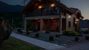 A log cabin with a stone foundation, a balcony, and a satellite dish.