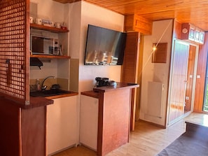 Cocina compacta con microondas, pileta y televisor de pantalla plana montado en la pared.