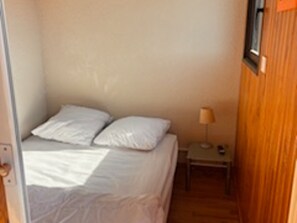 A small, narrow room with a single bed, a nightstand, and a window. - Les Angles - Cozy T2 Cabin 4 Pers (Les Angles)
