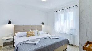Una camera da letto moderna con un letto, comodini, un tavolo da notte, una finestra con tende e un termosifone.