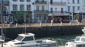 Uma marina com barcos atracados, uma farmácia e uma pastelaria.