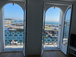 A room with two open doors leading to a balcony with a view of a marina and the sea. - Charming apartment in the heart of Le Croisic with port view (Le Croisic)