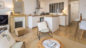 Uma cozinha moderna com uma ilha central, área de refeições com mesa e cadeiras, lareira e televisão.