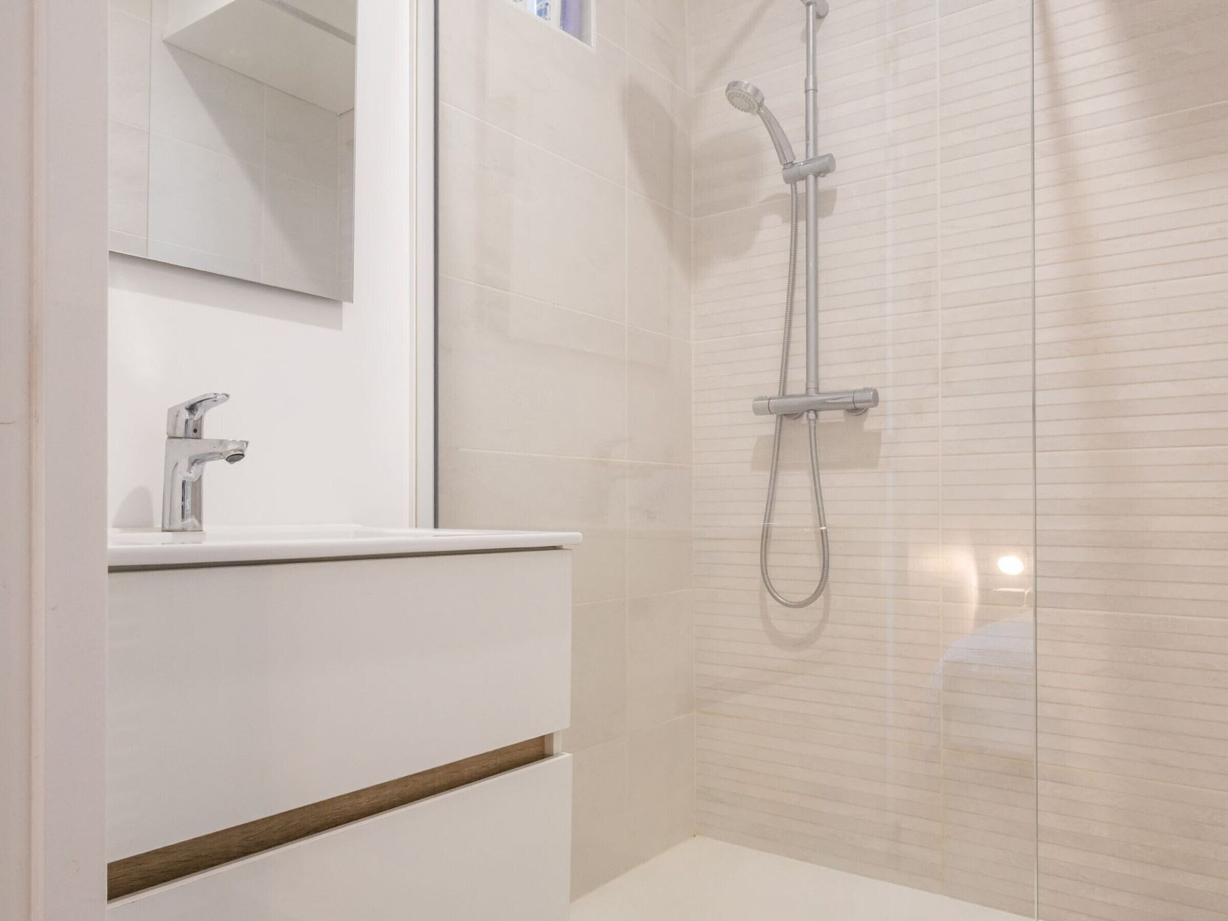 Une salle de bain moderne avec une douche, un lavabo et un miroir.