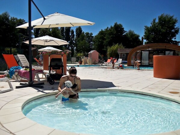 A swimming pool area with lounge chairs and umbrellas.