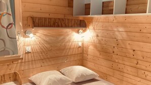A wooden cabin room with a bed, two pillows, and wall-mounted lights. - Chalet for 2 with Terrace in Montlaur (Montlaur)