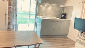 A compact kitchen with grey cabinets, a sink, and a coffee maker. There's a wooden table and a TV mounted on the wall. - Chalet for 2 with Terrace in Montlaur (Montlaur)