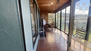 Un espacio al aire libre cubierto con techo de madera, ventanas grandes y piso de baldosas.