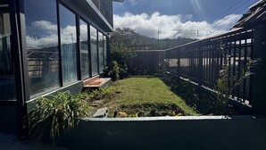 Un edificio moderno con amplios ventanales, un jardín bien cuidado y una vista despejada del cielo.
