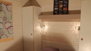 A bedroom with a bunk bed, a wardrobe, and a wall-mounted shelf with pictures. - Cozy Chalet for 4, Garden Terrace (Montlaur)