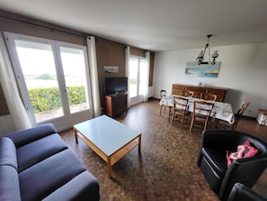 Un salon comprenant un canapé, une table basse, un téléviseur et un coin repas avec une table et des chaises.
