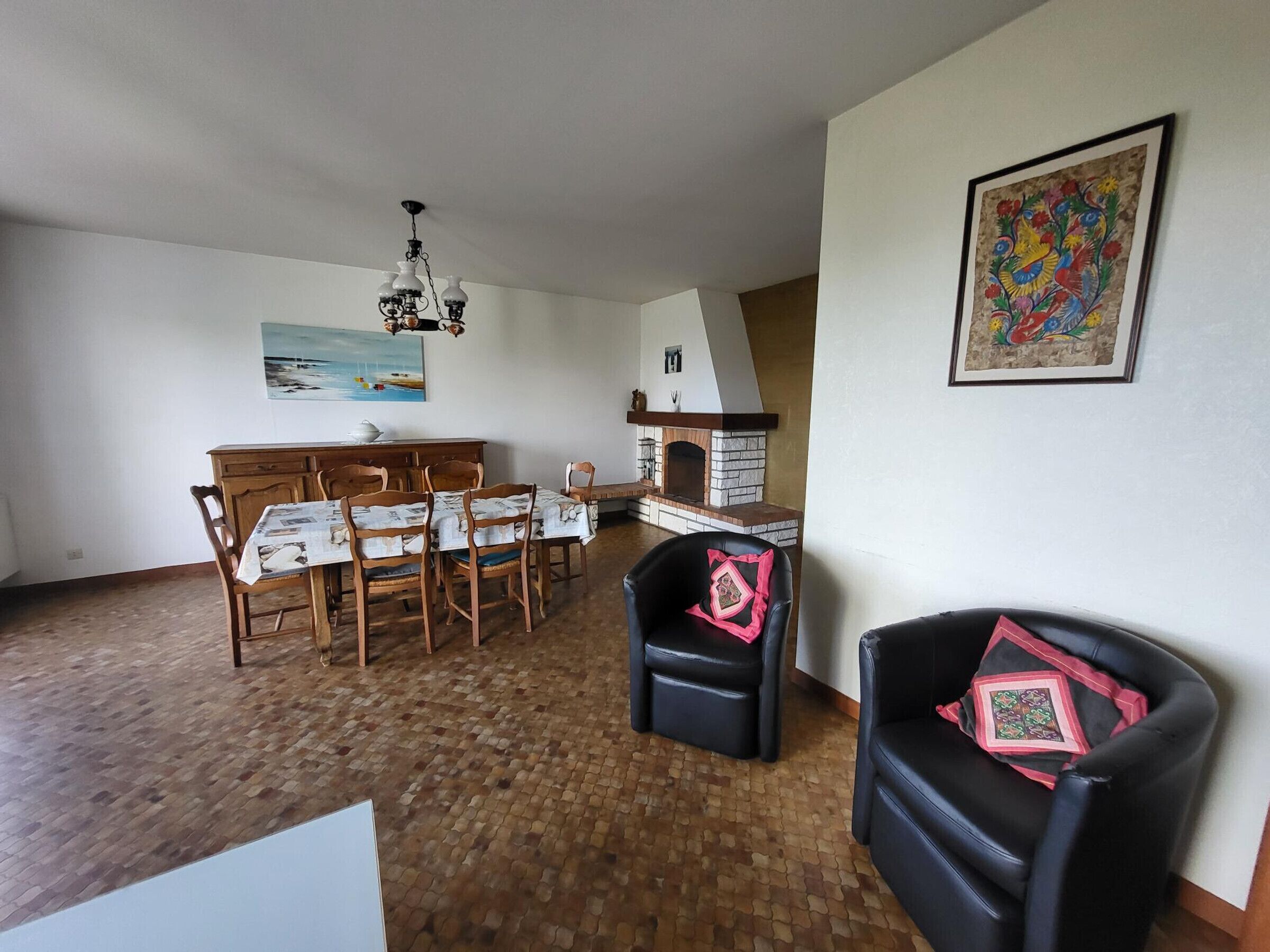 Un coin repas avec une table et des chaises en bois, une cheminée et un tableau au mur.