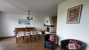 Een eethoek met een houten tafel en stoelen, een open haard en een schilderij aan de muur.
