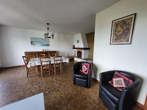 Ein Essbereich mit Holztisch und -stühlen, einem Kamin und einem Gemälde an der Wand.