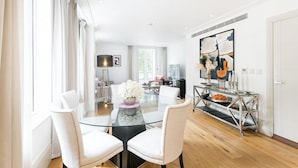 Un comedor moderno con una mesa de vidrio, sillas blancas y un jarrón decorativo.