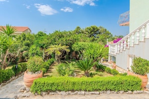 A garden with various plants and a staircase leading to a building. - Charming Holiday Home in Maslenica (Maslenica)