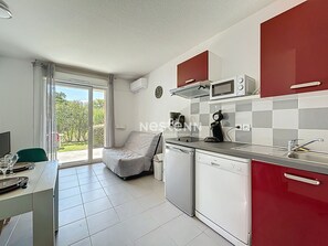 Eine moderne Küche mit roten Schränken, einer Mikrowelle und einer Kaffeemaschine. Eine Glastür führt auf einen Balkon.
