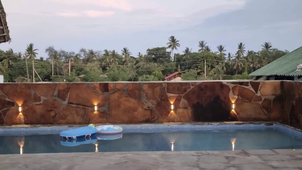 Une piscine avec des murs en pierre et un éclairage intégré.