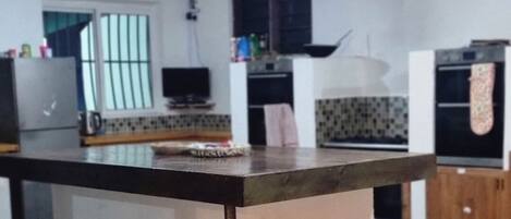 A kitchen with a central island, a refrigerator, and a microwave.