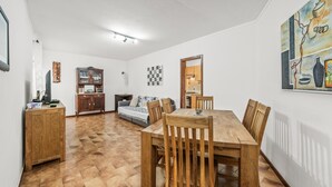 Ein Essbereich mit Holztisch und Stühlen, einer Couch, einem Schrank und einem Bild an der Wand.
