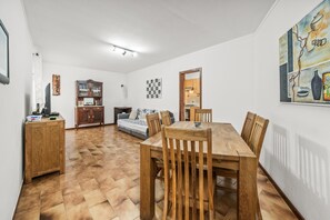 Un coin repas avec une table et des chaises en bois, un canapé, un meuble et un tableau accroché au mur.