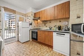 Une cuisine équipée d’armoires en bois, d’un réfrigérateur, d’une cuisinière, d’un lave-vaisselle et d’un four à micro-ondes.