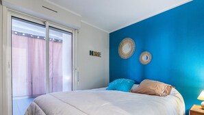 Un dormitorio con una cama, puerta corrediza de vidrio y pared azul.