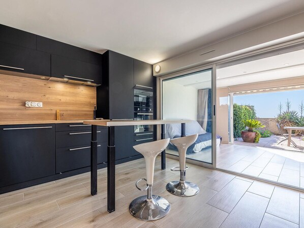 A modern kitchen with dark cabinetry, a wooden countertop, and a bar area with two white bar stools.