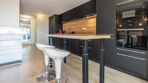 Una cocina moderna con armarios oscuros, encimera de madera y horno empotrado.